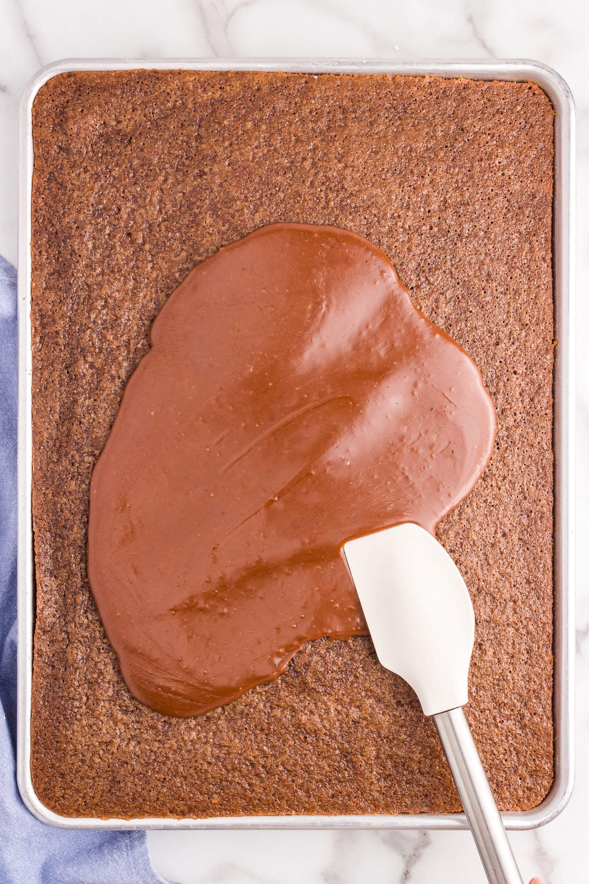 Using a spatula to evenly spread frosting over Texas Sheet Cake