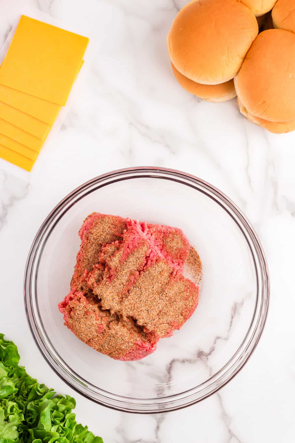 Adding beef seasoning to ground beef in mixing bowl for Hamburgers Baked in the Oven