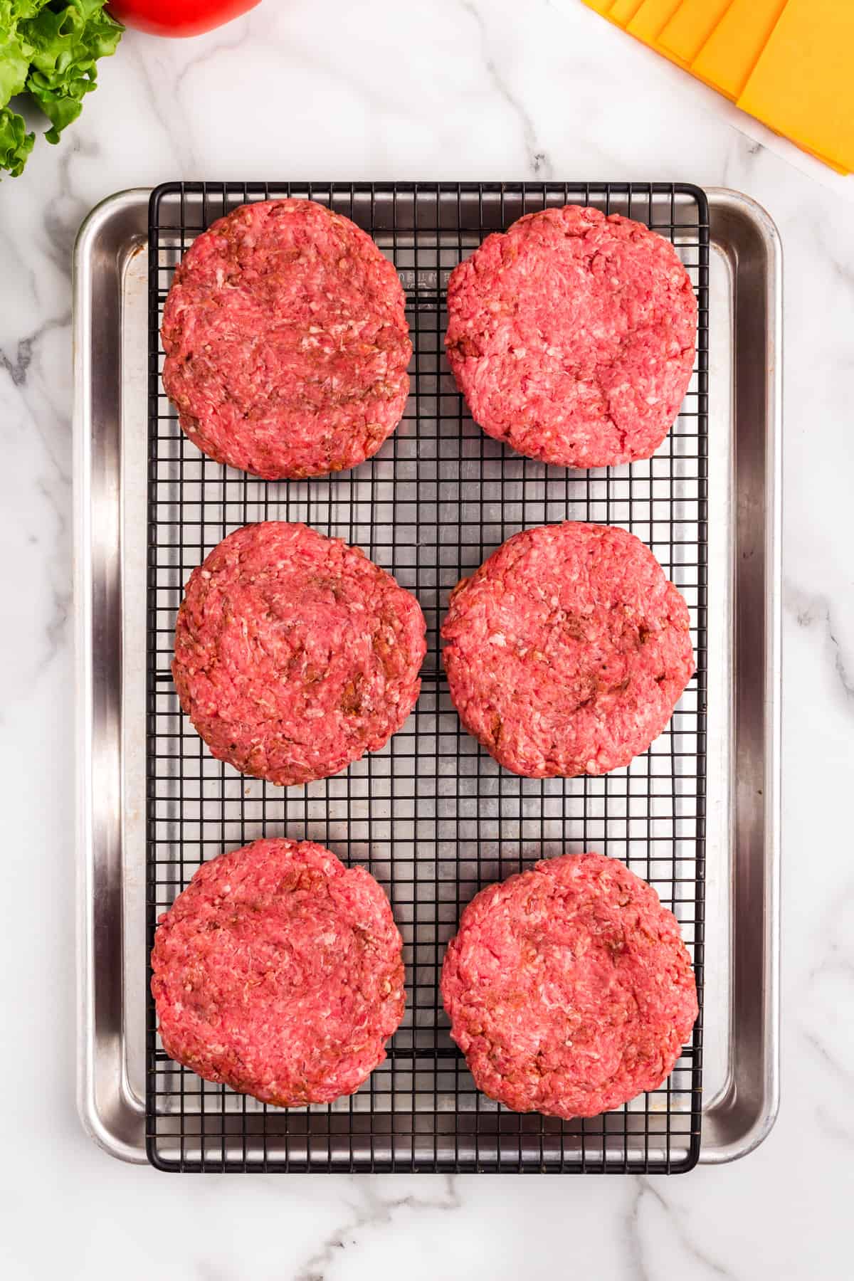 Seasoned ground beef patties on cooking grate for Baked Hamburgers recipe
