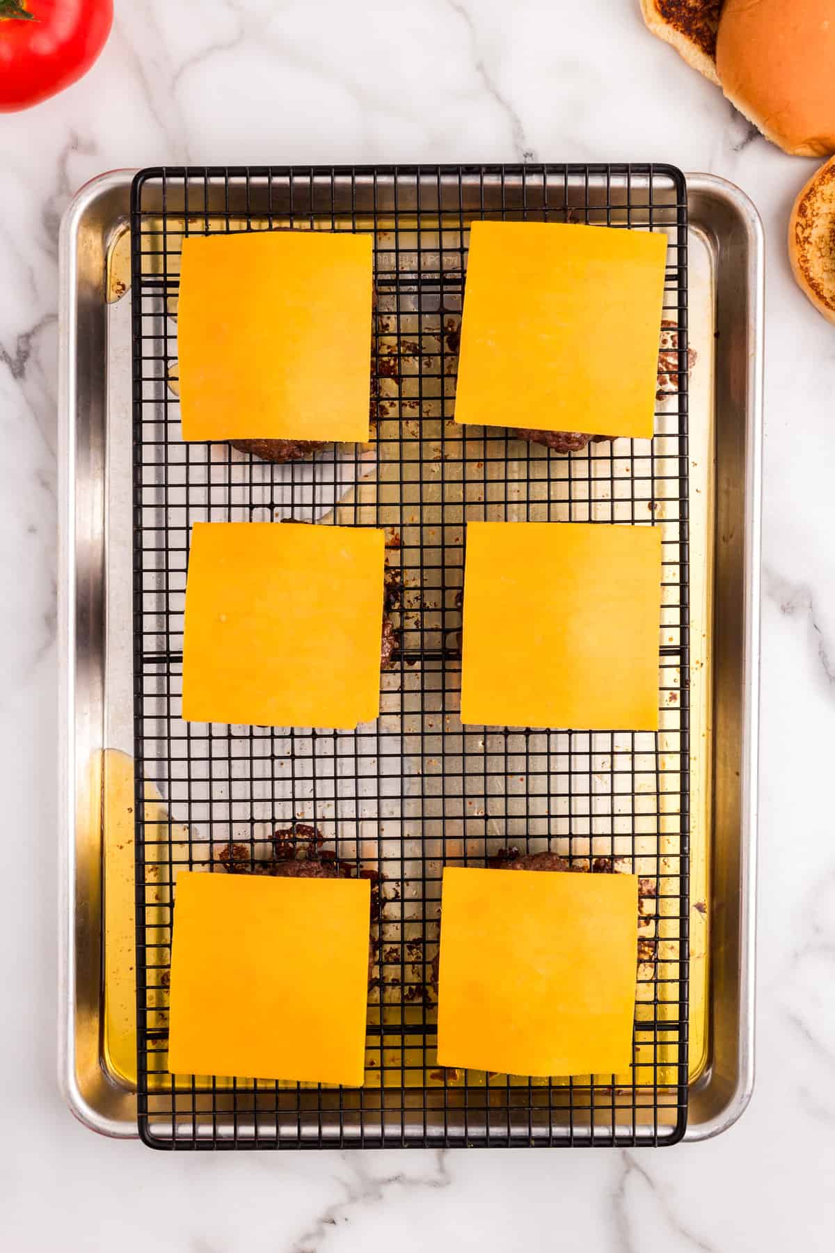 Adding sliced cheddar cheese to Baked Hamburgers on cooking grate