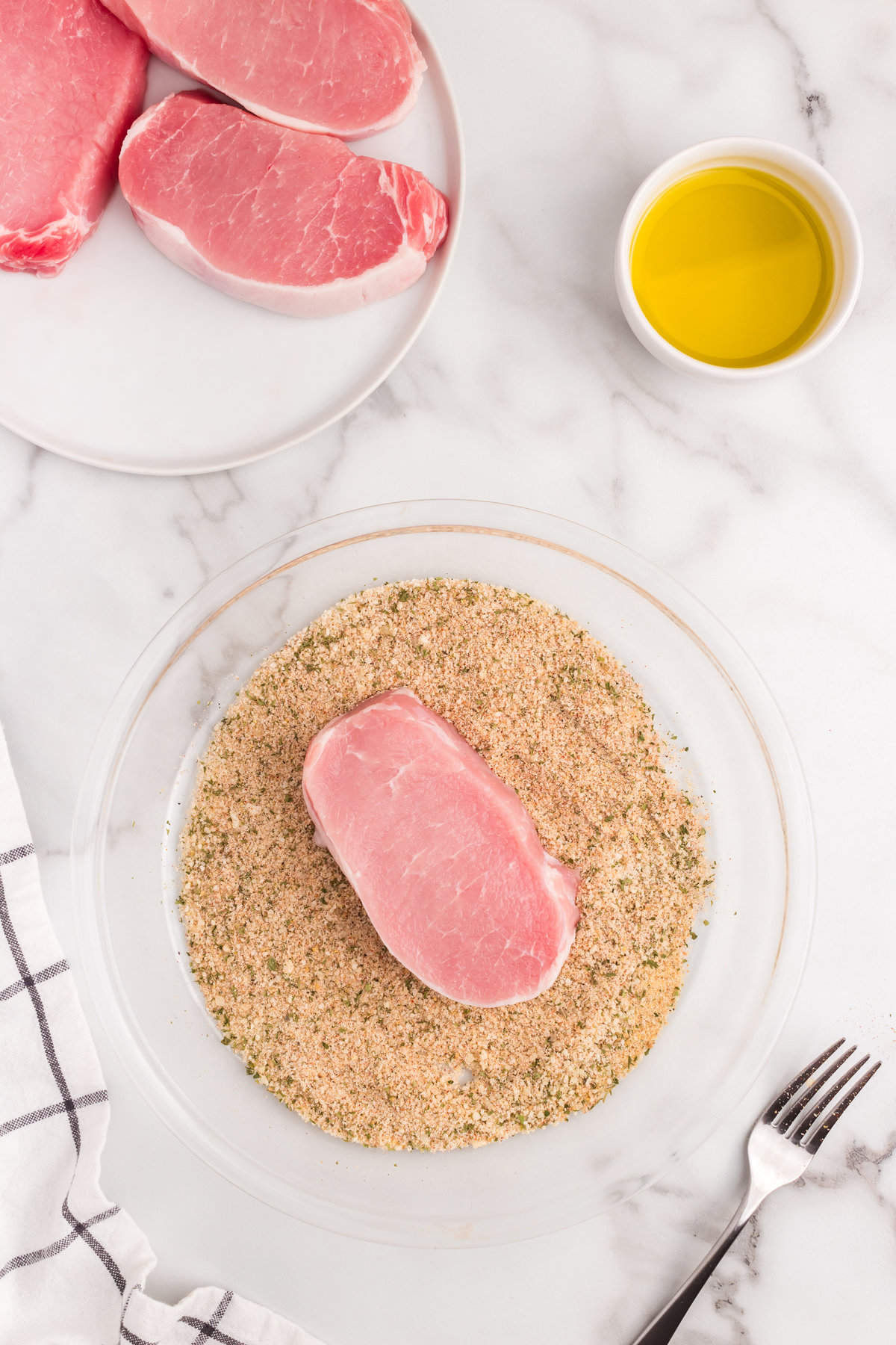 With combined seasonings in bowl a boneless pork chop slice is added for the Parmesan Crusted Pork Chops recipe