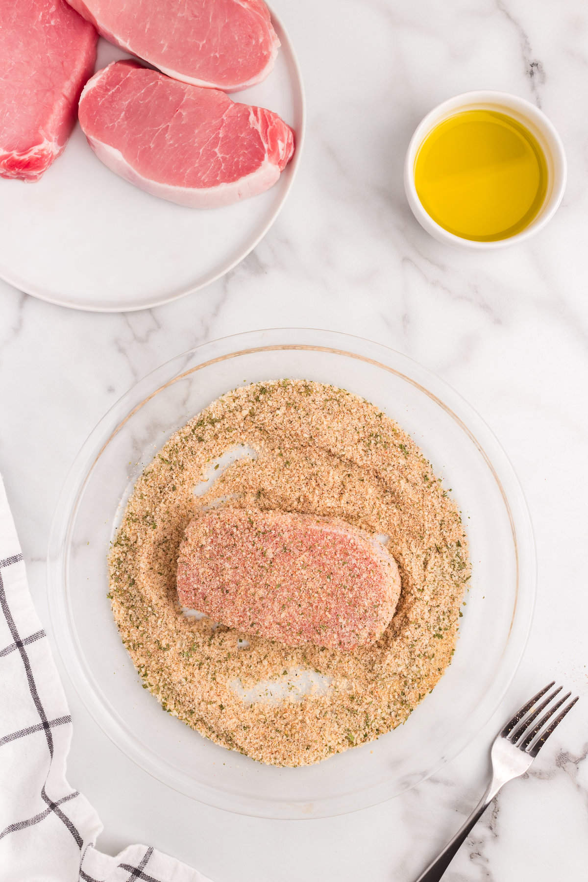 Coating a pork chop with the combined seasoning for Parmesan Crusted Pork Chops