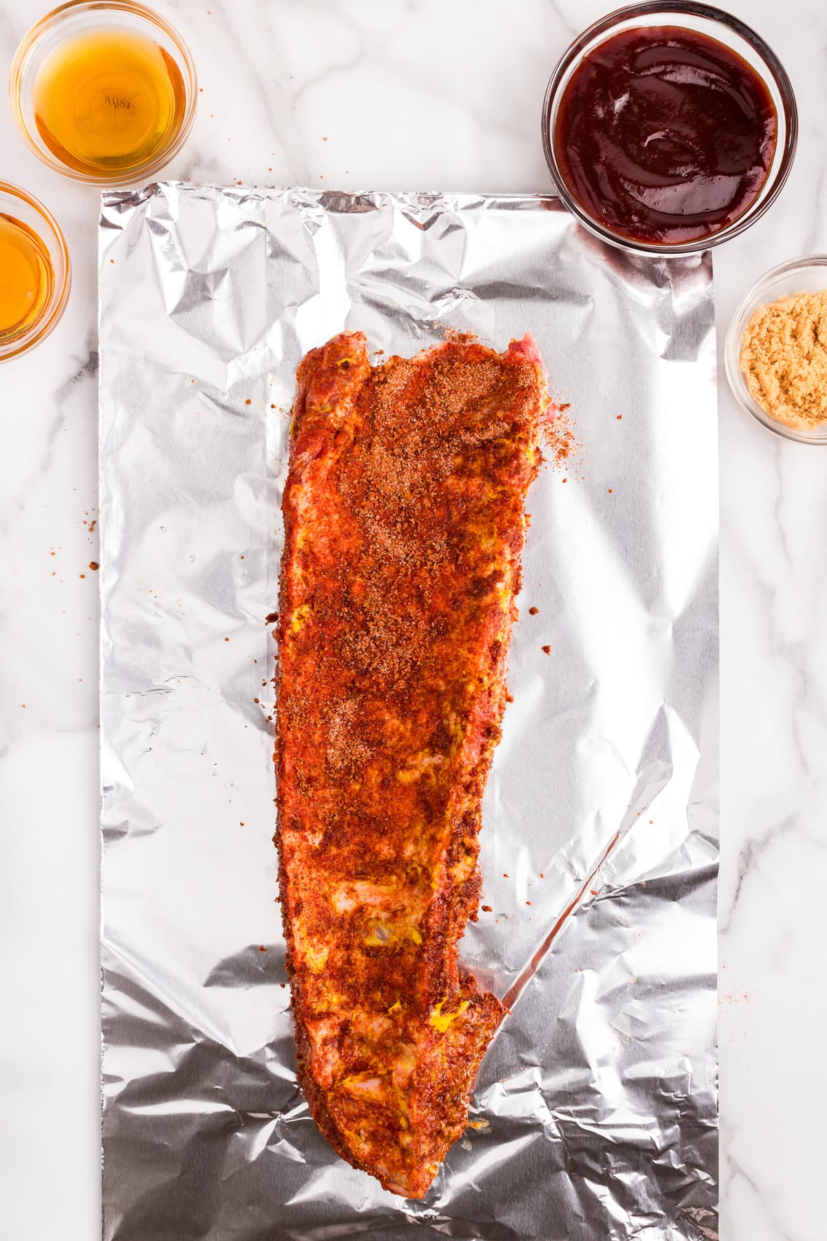 Moving the seasoned ribs to tin foil piece for baking for Oven Baked Pork Ribs recipe