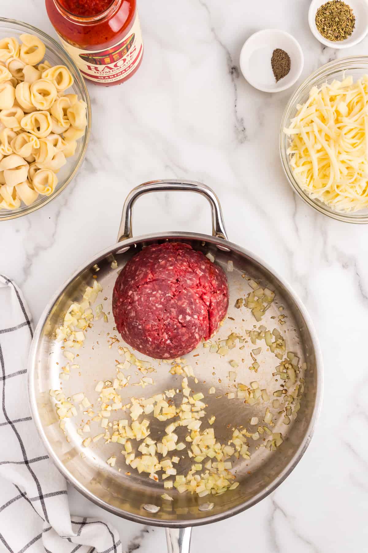 Ground beef and other seasonings in stovetop skillets for Baked Tortellini recipe