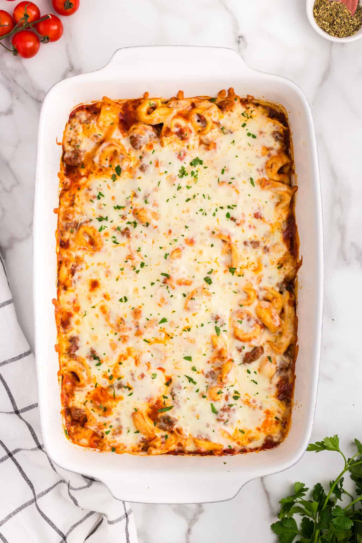 Baked Tortellini topped with shredded cheese just out of the oven in a baking dish