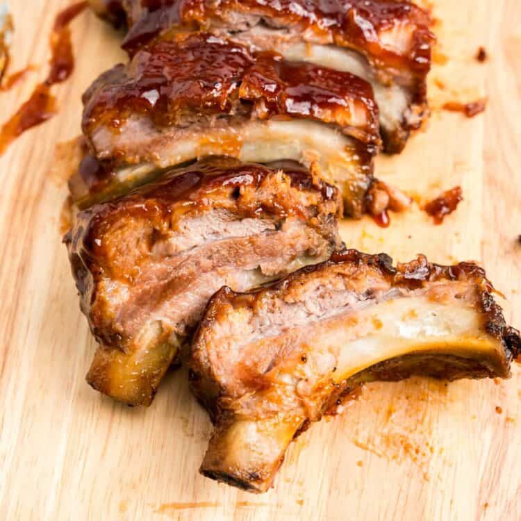 Square image of Oven Baked Ribs sliced on wooden cutting board