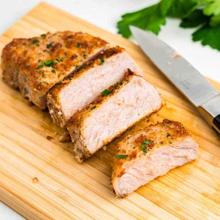 Parmesan Crusted Pork Chops sliced on wooden cutting board