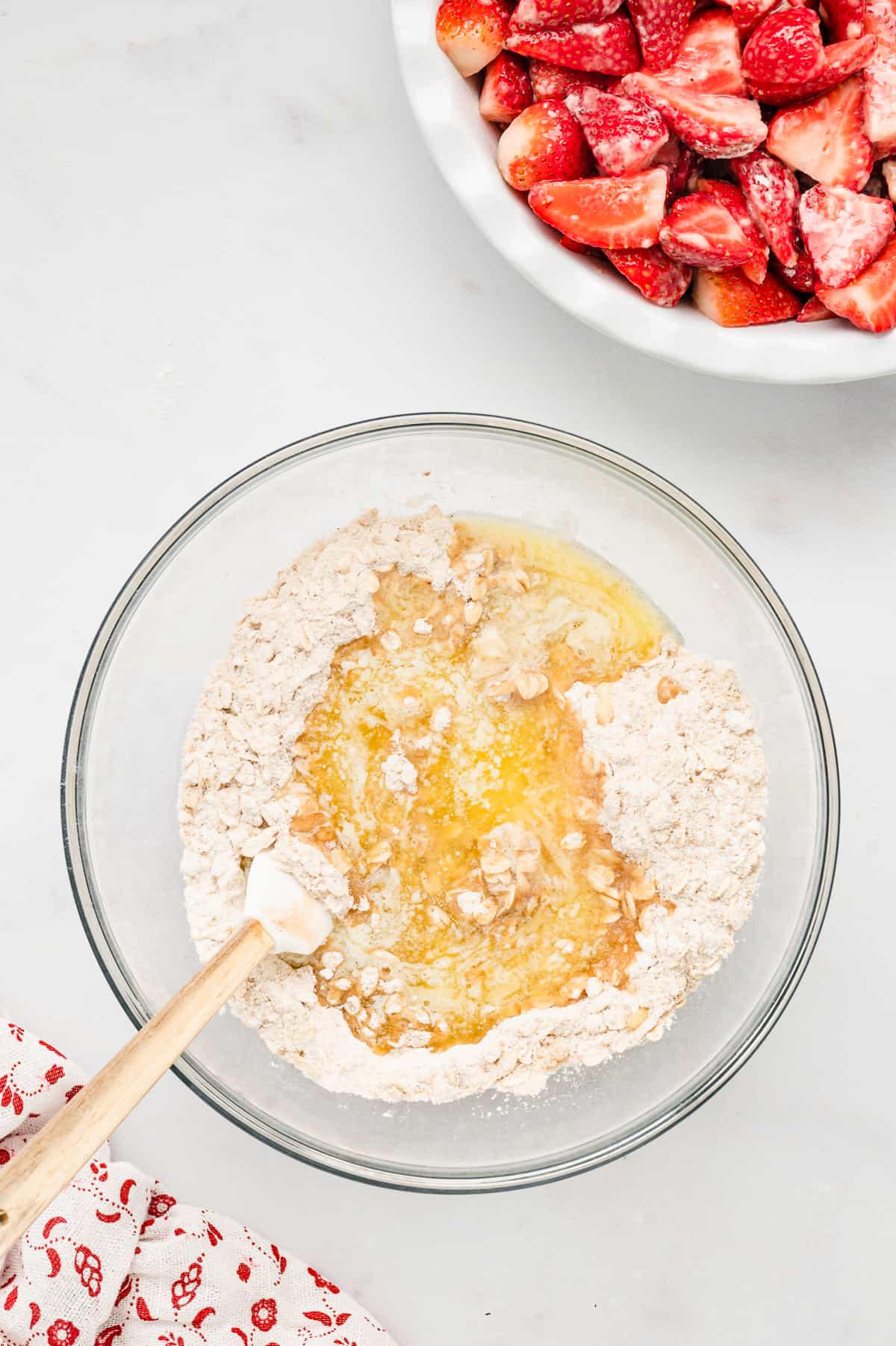 Stirring Topping Ingredients in a Glass Bowl with a Wooden Spoon for Strawberry Crisp Recipe