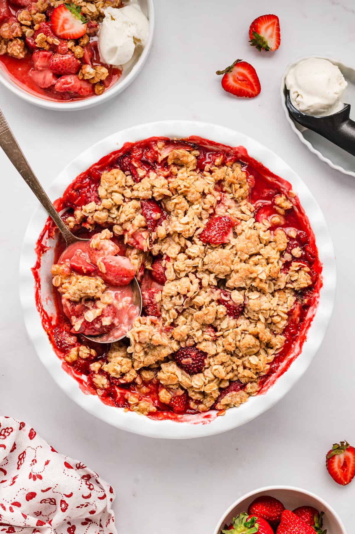 Strawberry Crisp hot out of the oven in round baking dish with spoon for Strawberry Crisp recipe