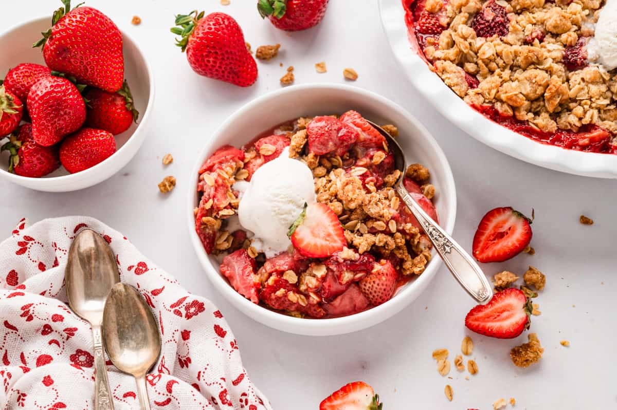 Strawberry Crisp topped with vanilla ice cream in bowl with spoon