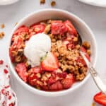 Strawberry Crisp in bowl topped with vanilla ice cream
