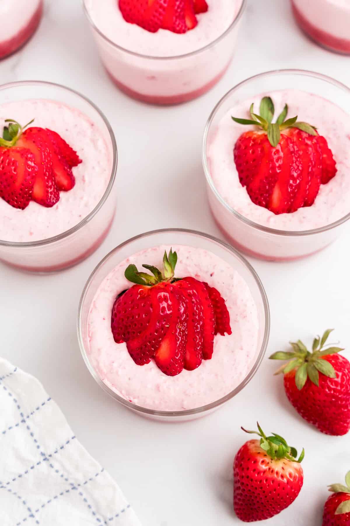 Fanning sliced strawberries atop the creamy puree layer in glass for Looking for a refreshing and easy dessert? Try this delicious strawberry mousse recipe made with fresh strawberries, perfect for any occasion. Light and airy, it's sure to become a crowd favorite! recipe