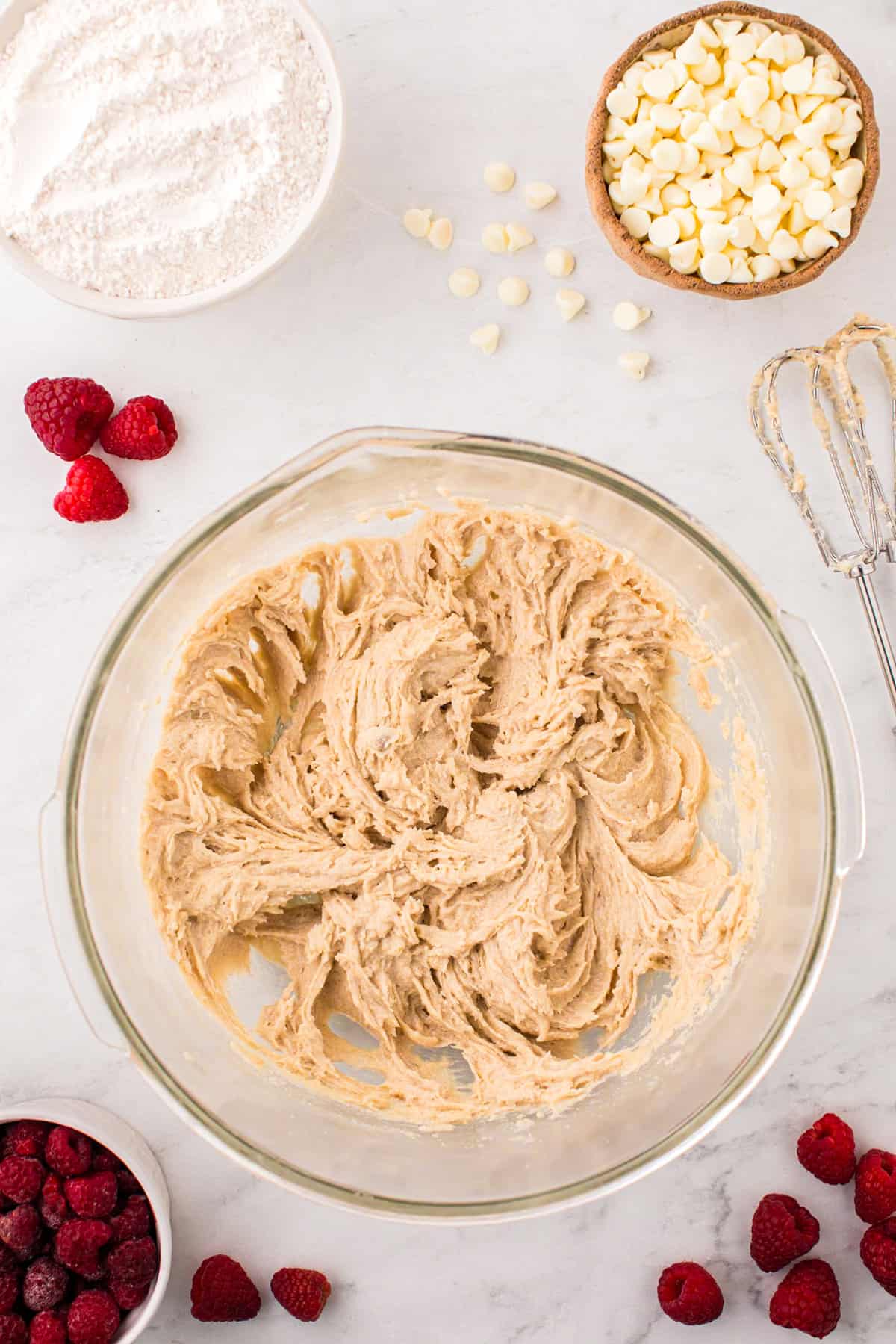 Creamed sugars, egg, and butter in glass mixing bowl for Raspberry White Chocolate Cookies