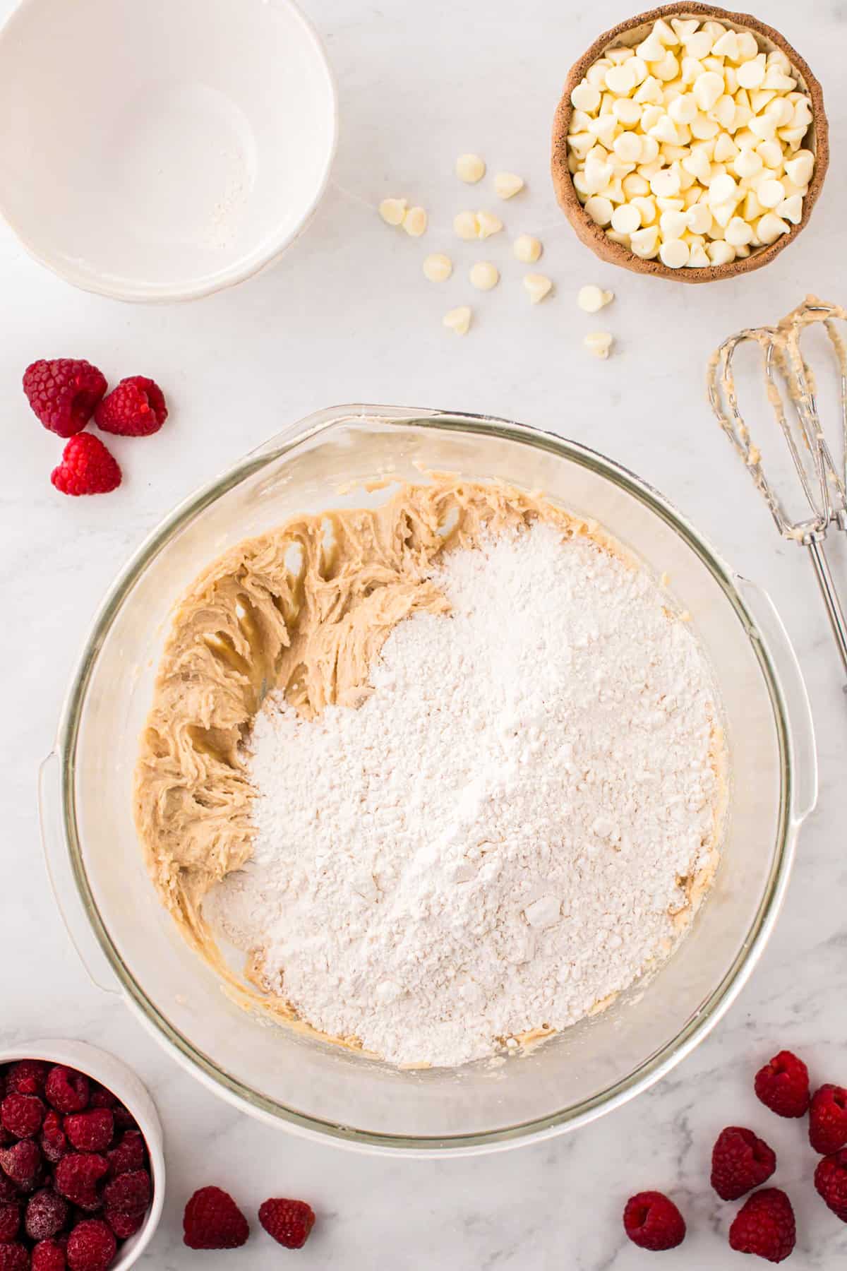 Adding flour to creamed mixture in bowl for Raspberry White Chocolate Cookies