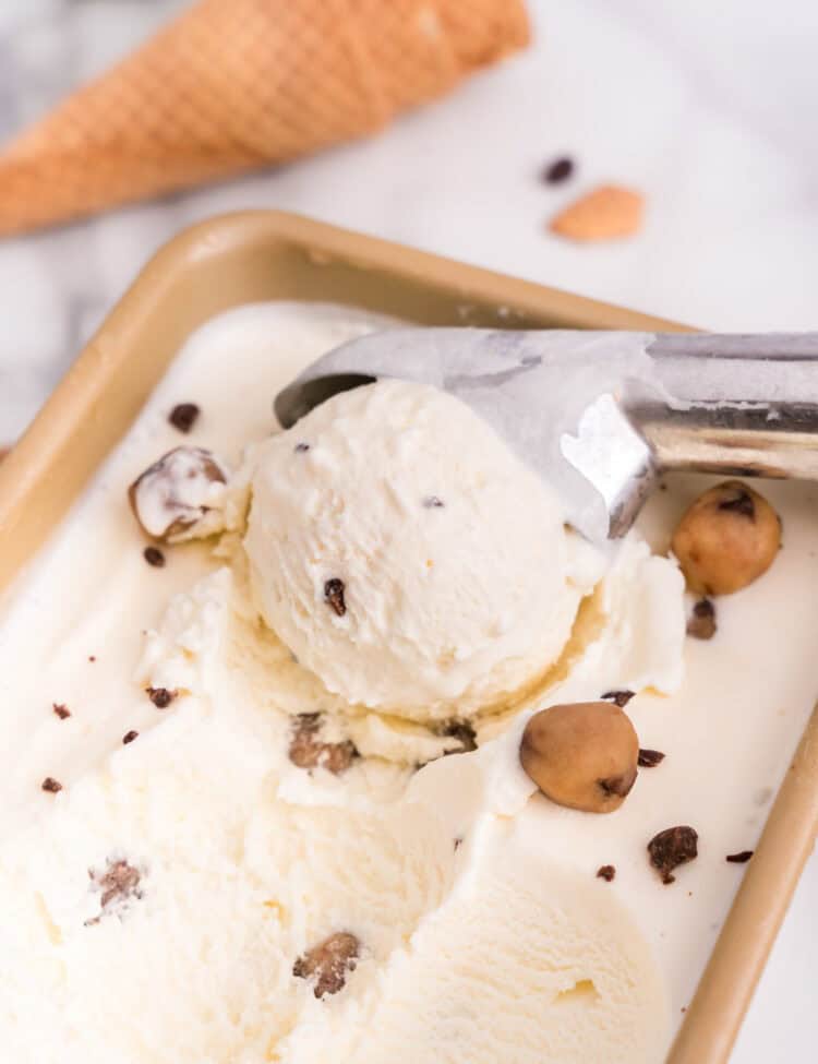 Using ice cream scoop to pull Cookie Dough Ice Cream from the pan