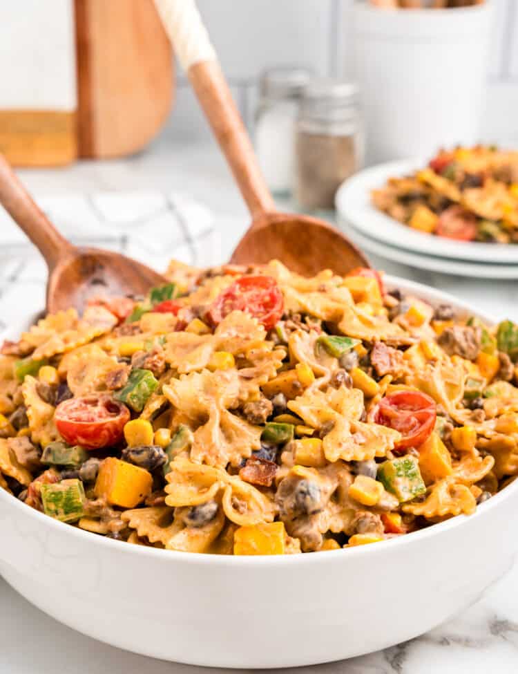 Cowboy Pasta Salad in serving bowl with wooden serving spoons