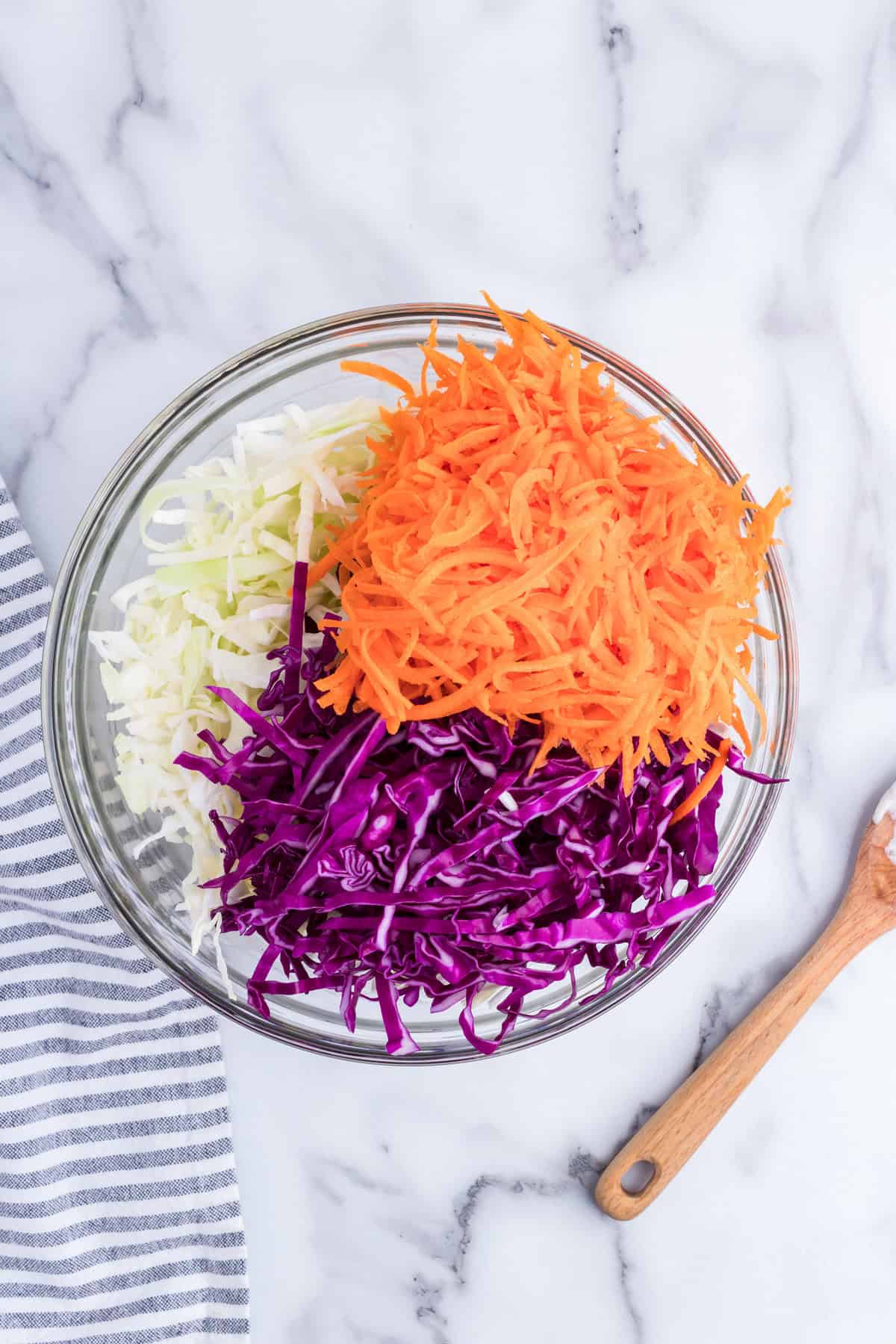 Adding shredded cabbages and carrots to Creamy Coleslaw dressing in mixing bowl