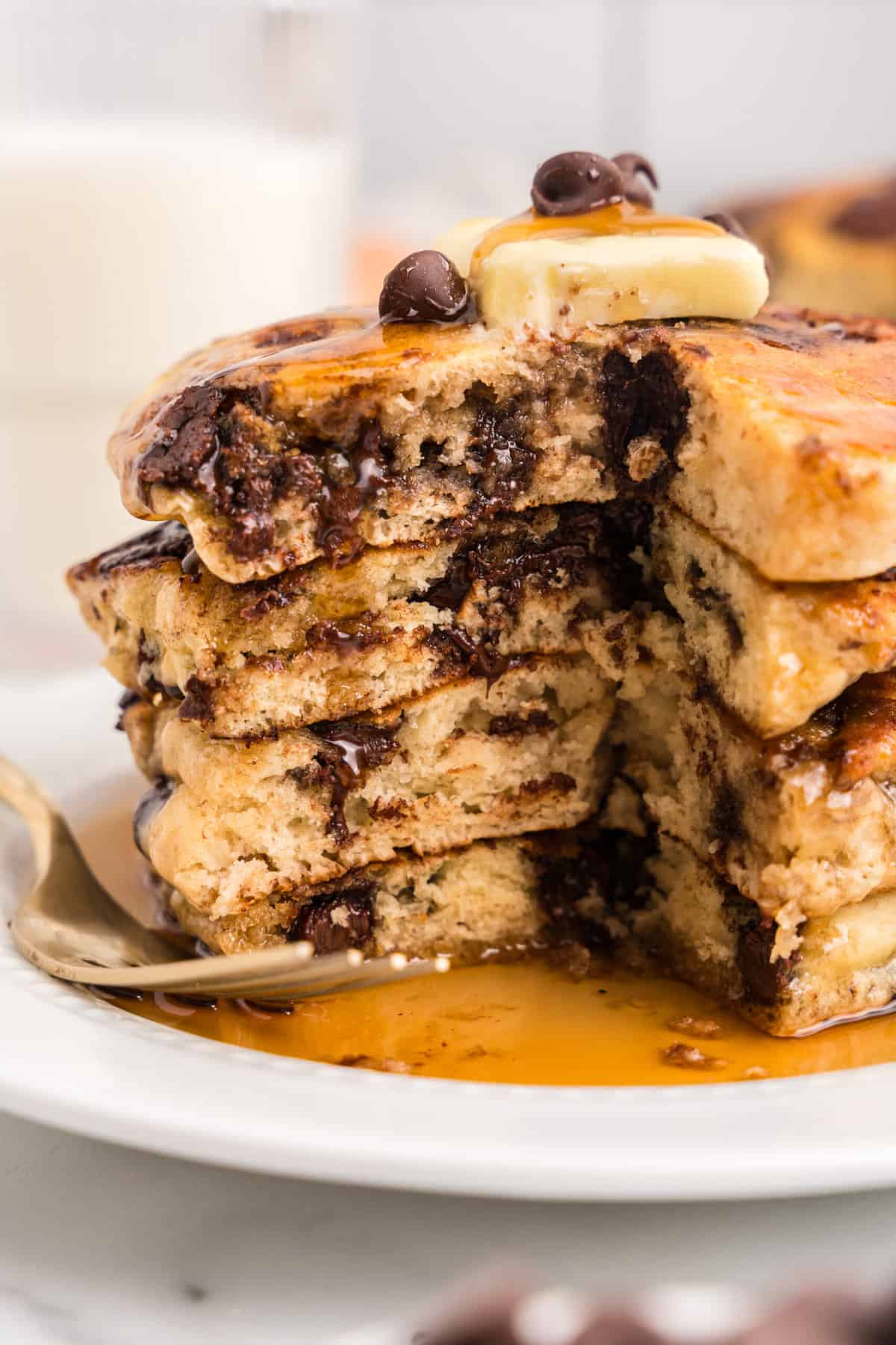 a Stack of pancakes with a big bite cut out of them to show the fluffly inside to the pancakes.