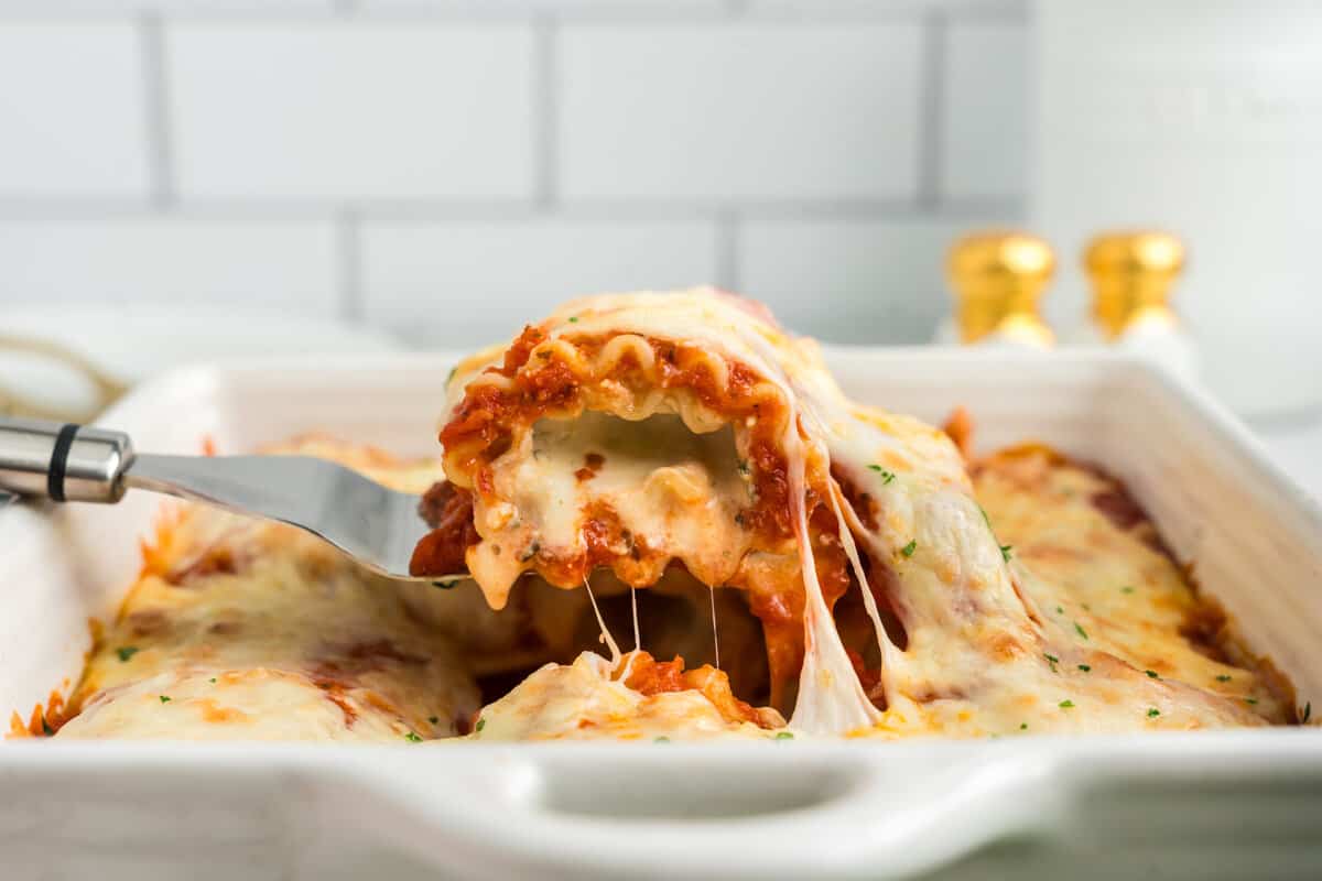 Using a spatula to pull Lasagna Roll Ups from baking pan