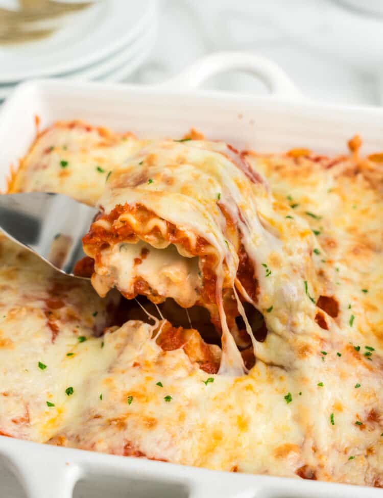 Pulling Lasagna Roll Ups piece from baking pan