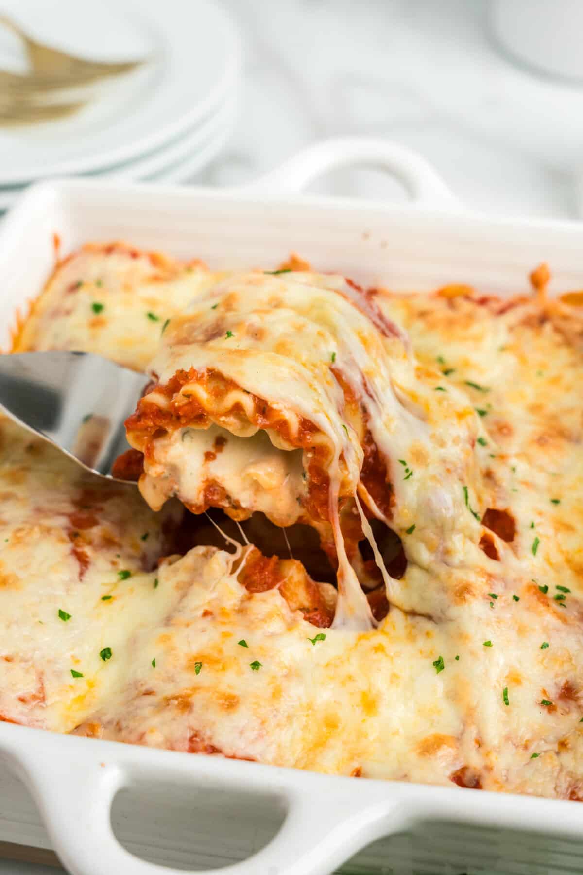 Pulling Lasagna Roll Ups piece from baking pan