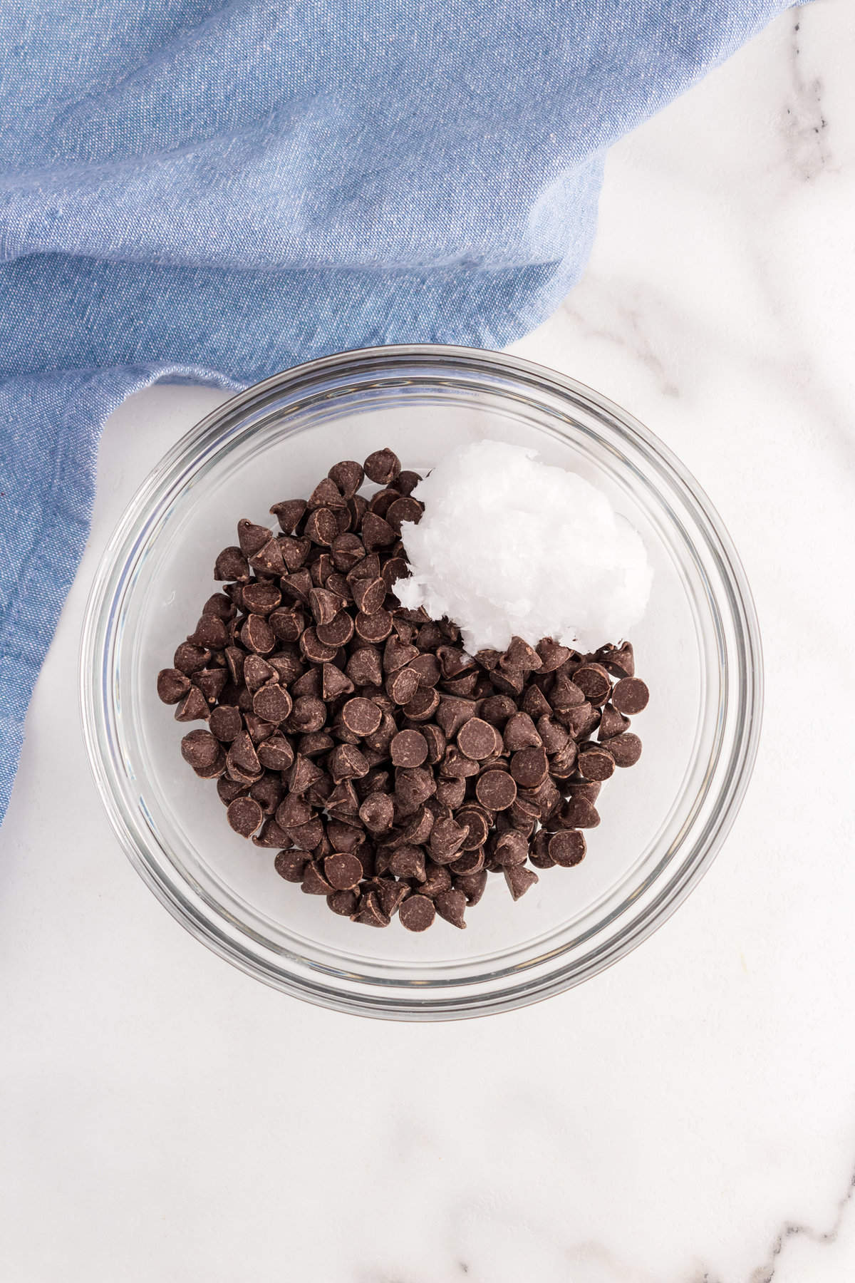 Semi-sweet chocolate chips and coconut oil in mixing bowl for Homemade Magic Shell recipe