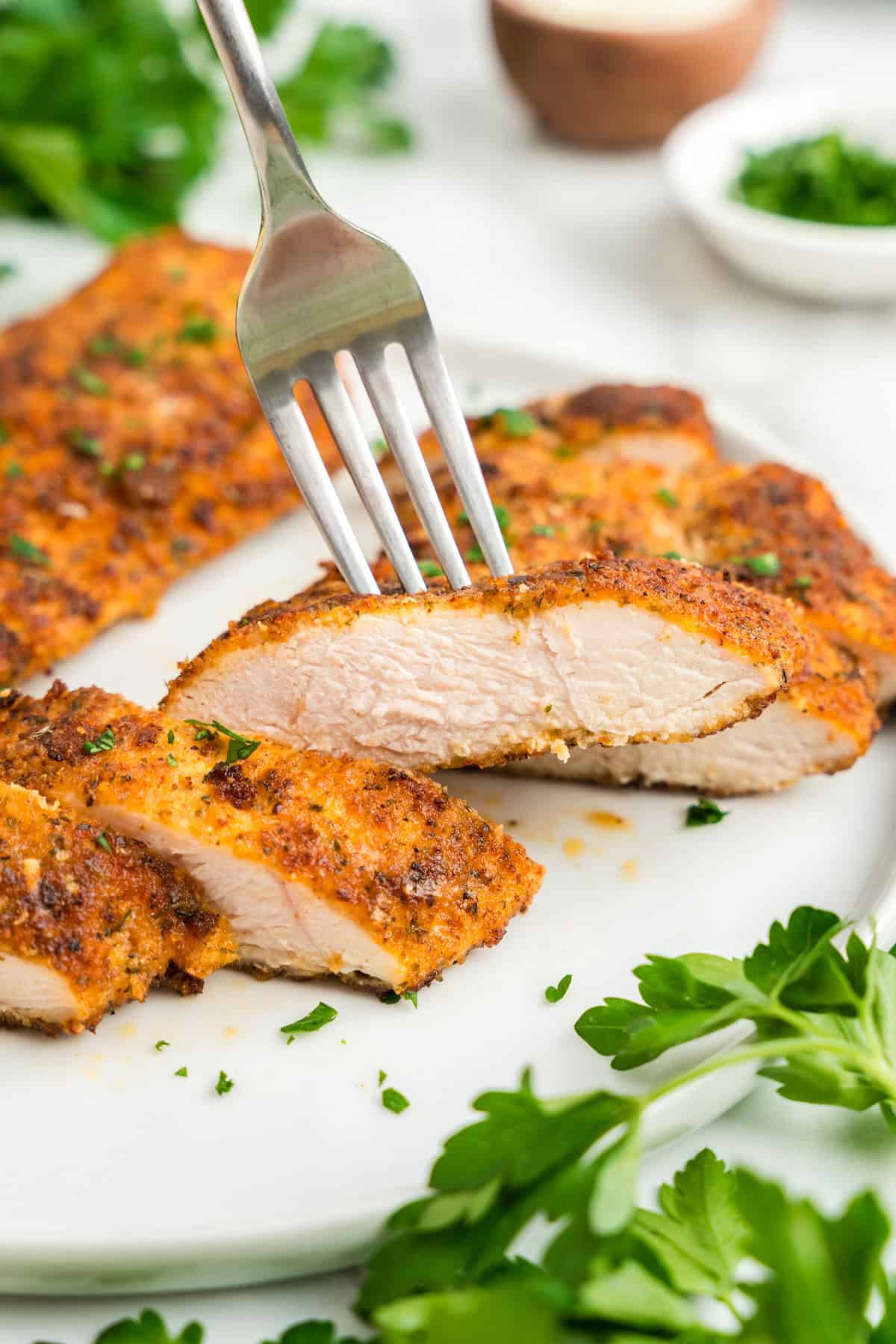 Parmesan Crusted Chicken on white plate, sliced with a fork