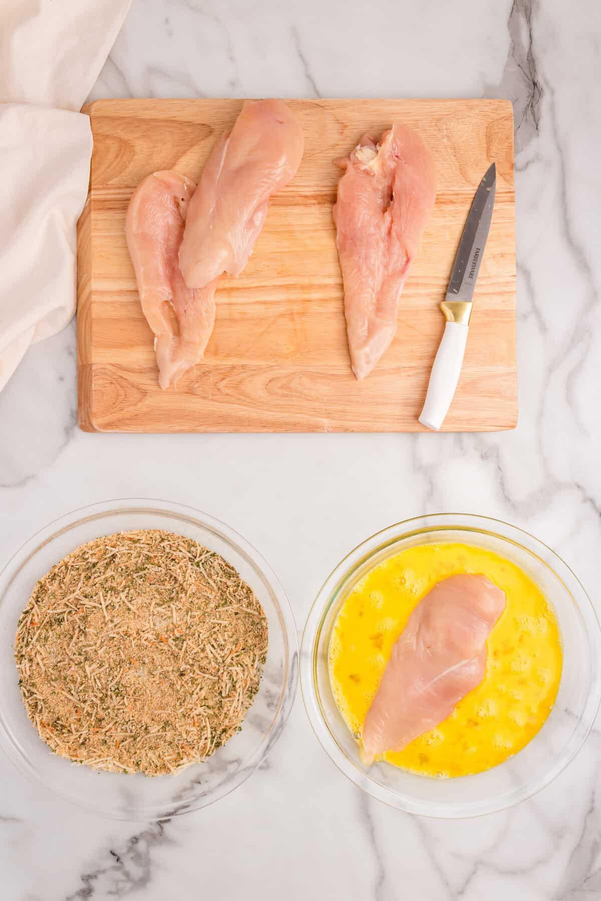 Dipping chicken breast in egg mixture to coat with seasoning for Parmesan Crusted Chicken recipe