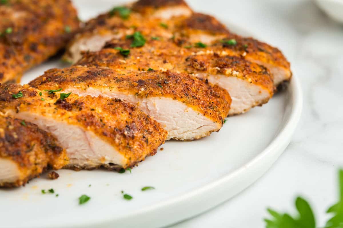Chicken crusted with parmesan sliced on white plate ready to enjoy
