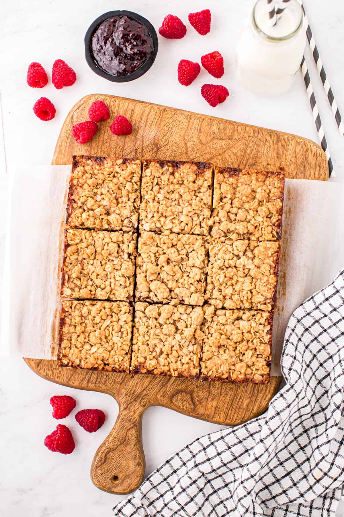 Raspberry Crumble Bars baked to golden brown on wooden cutting board cut into squares