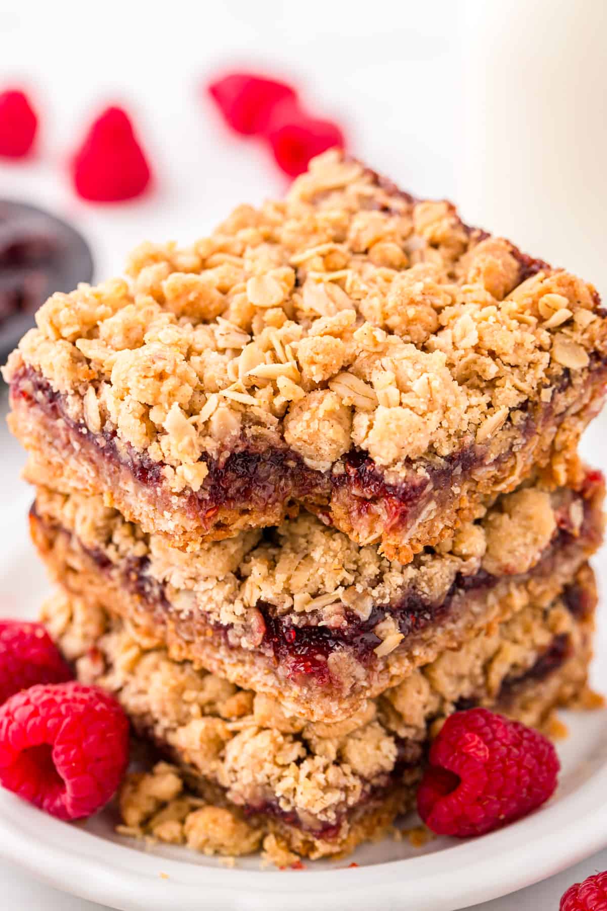 Raspberry Crumble Bars cut into square stacked with one bite taken