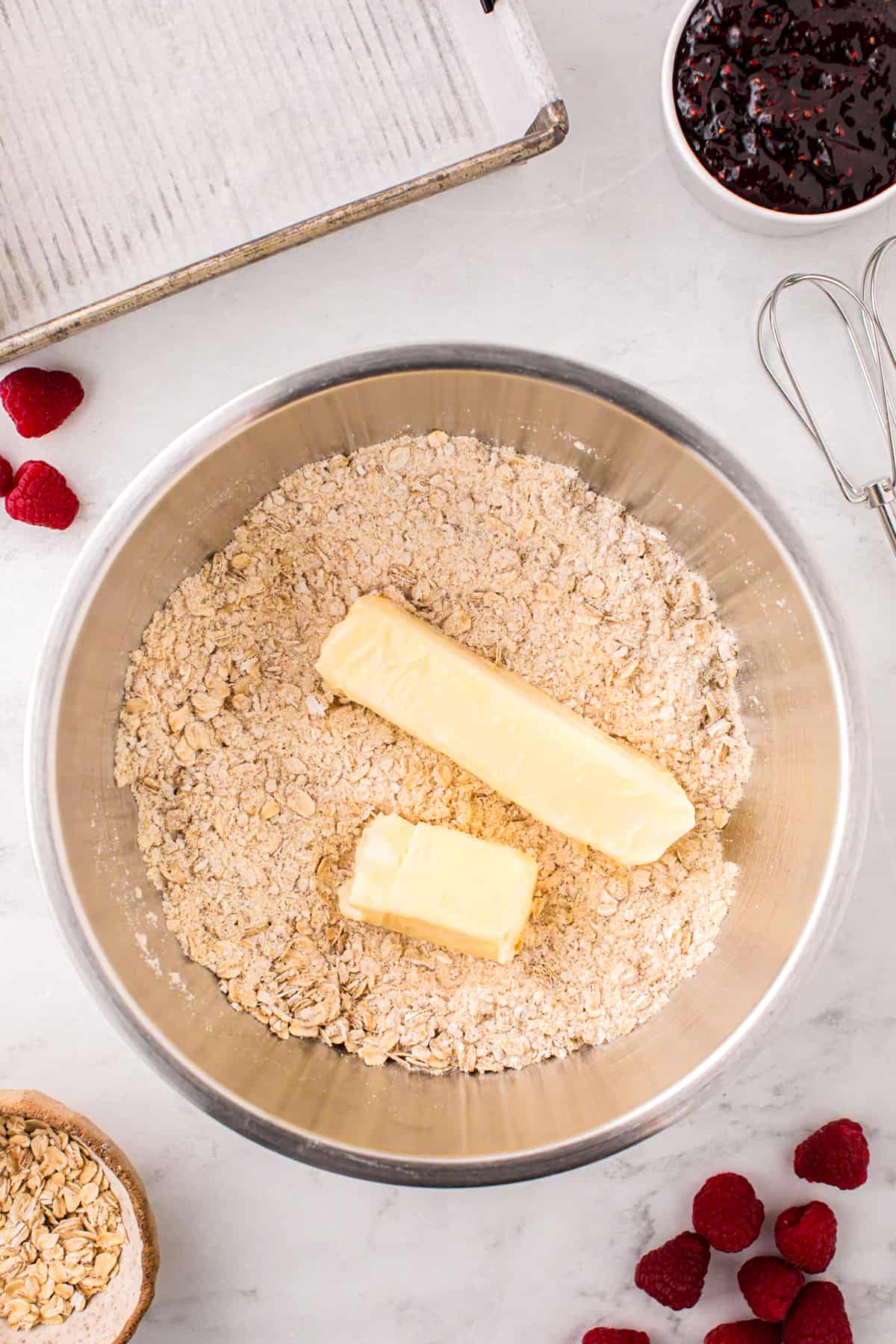 Adding butter to dry ingredients to mixing bowl for Raspberry Crumble Bars 