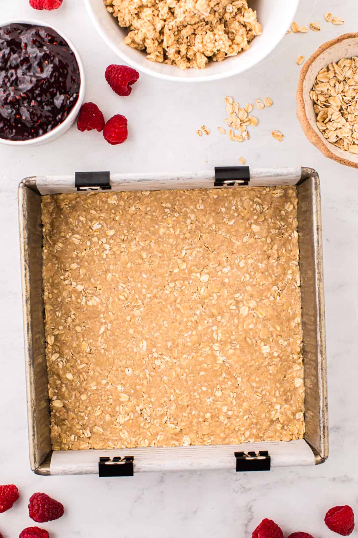 Presssing oat meal crust into square pan for Raspberry Crumble Bars