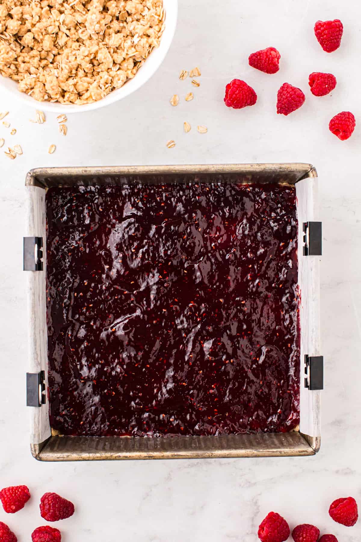 Spreading raspberry preserves over crust for Raspberry Crumble Bars