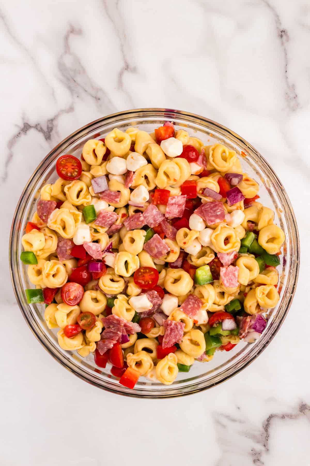 Tossing Tortellini Pasta Salad ingredients in large mixing bowl