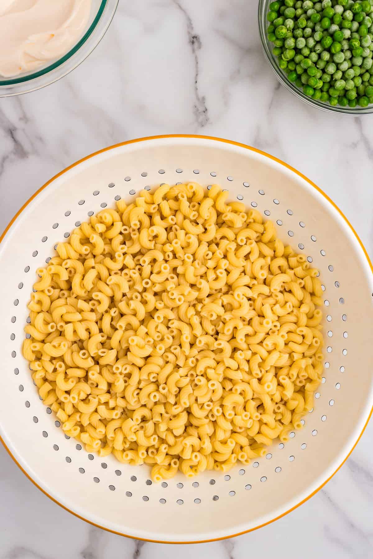 Cooked pasta noodles in strainer for Chicken Macaroni Salad