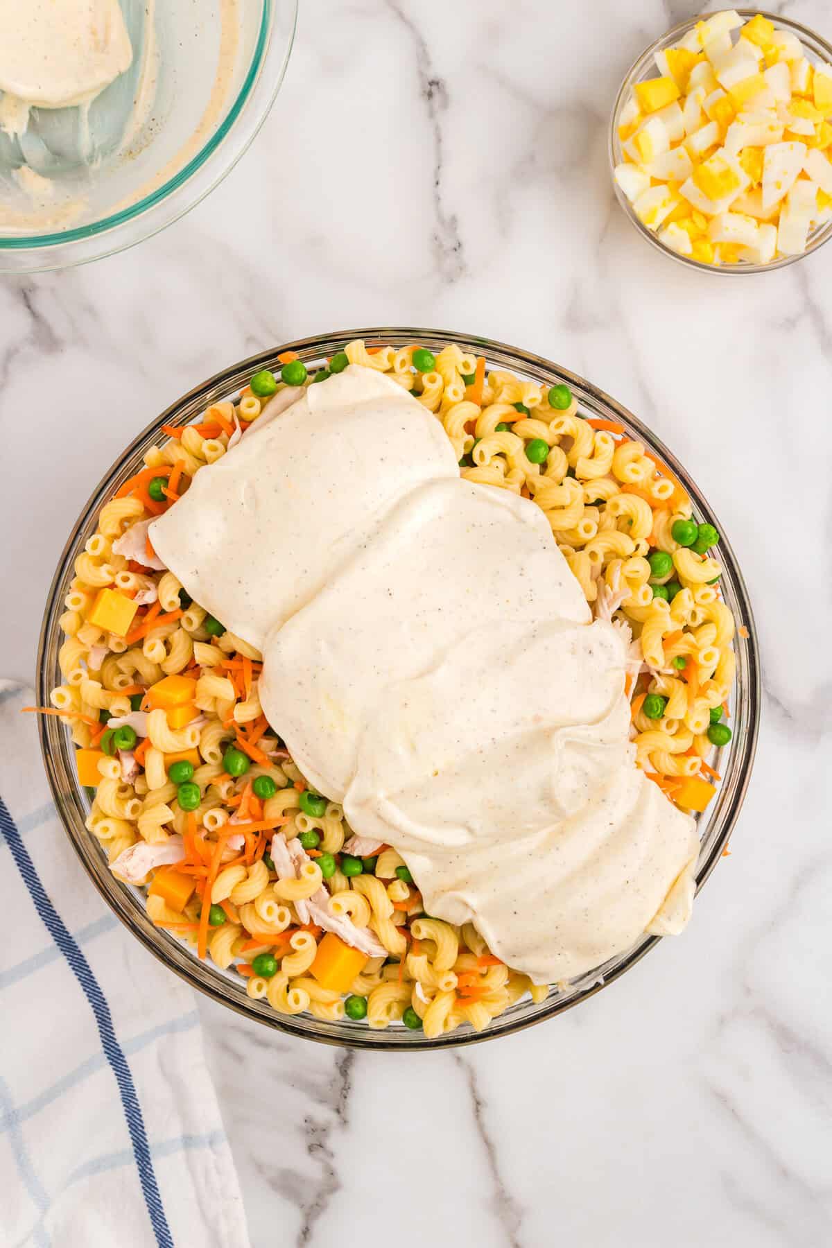 Dressing poured over tossed Chicken Macaroni Salad ingredients in large bowl