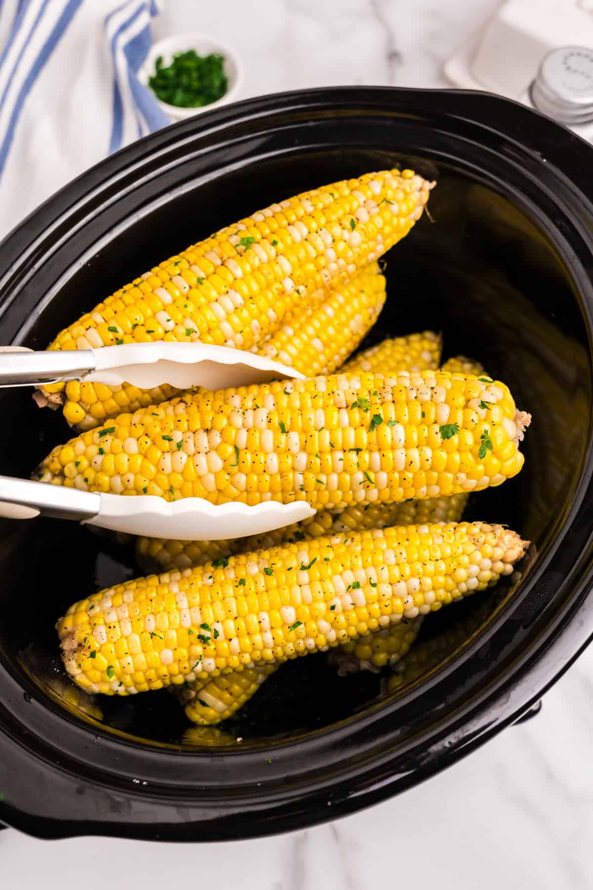 Using tongs to take corn out for Crock Pot Corn on the Cob recipe