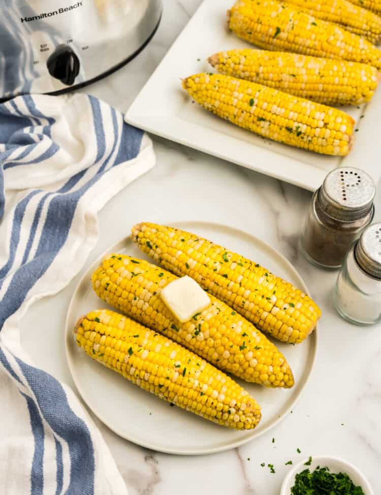Crock Pot Corn on the Cob arranged on plate with a pad of butter melting