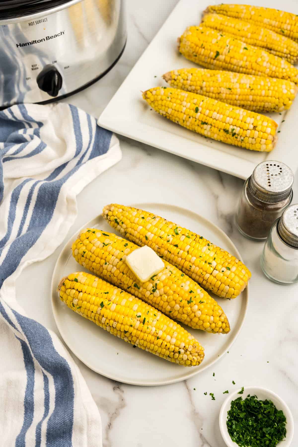 Crock Pot Corn on the Cob arranged on plate with a pad of butter melting
