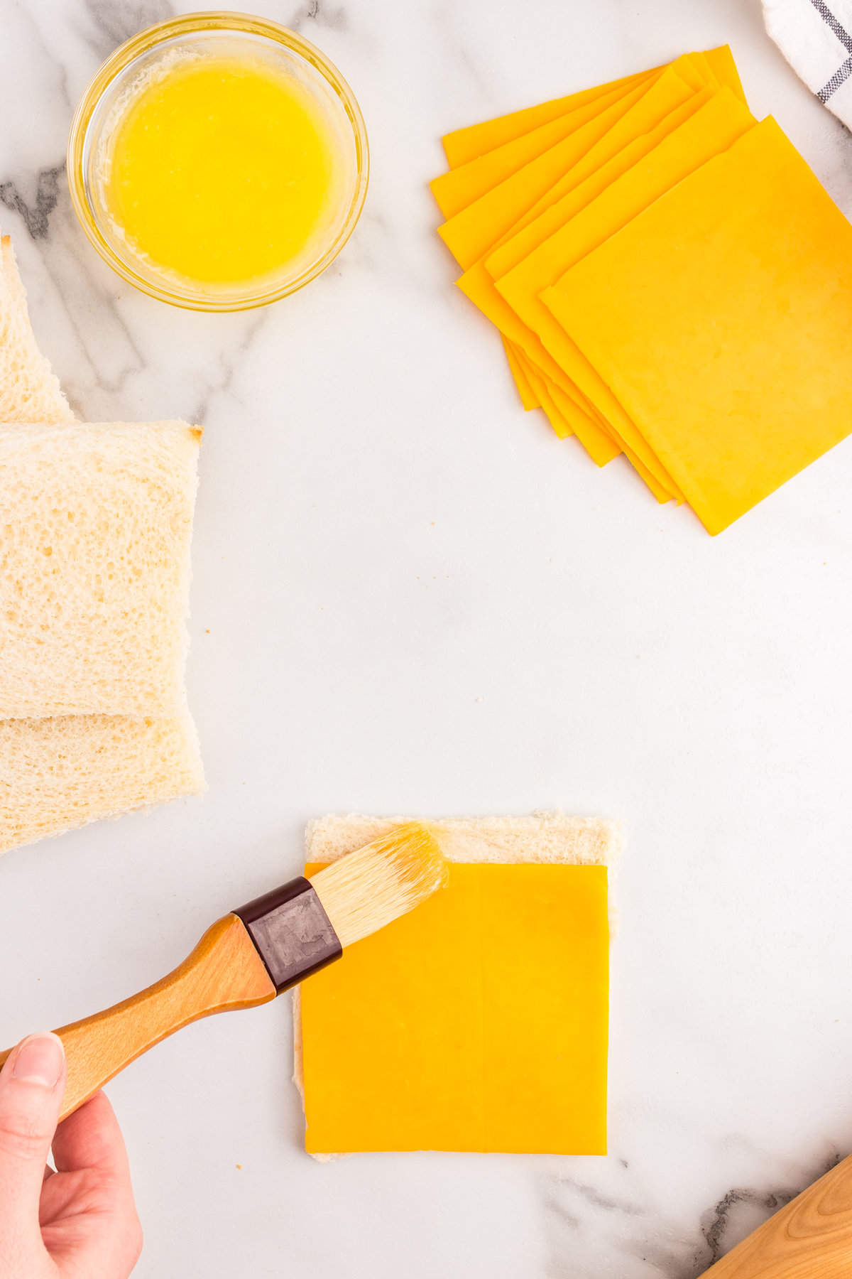 Place a slice of cheese onto the bread leaving a strip to brush with butter.