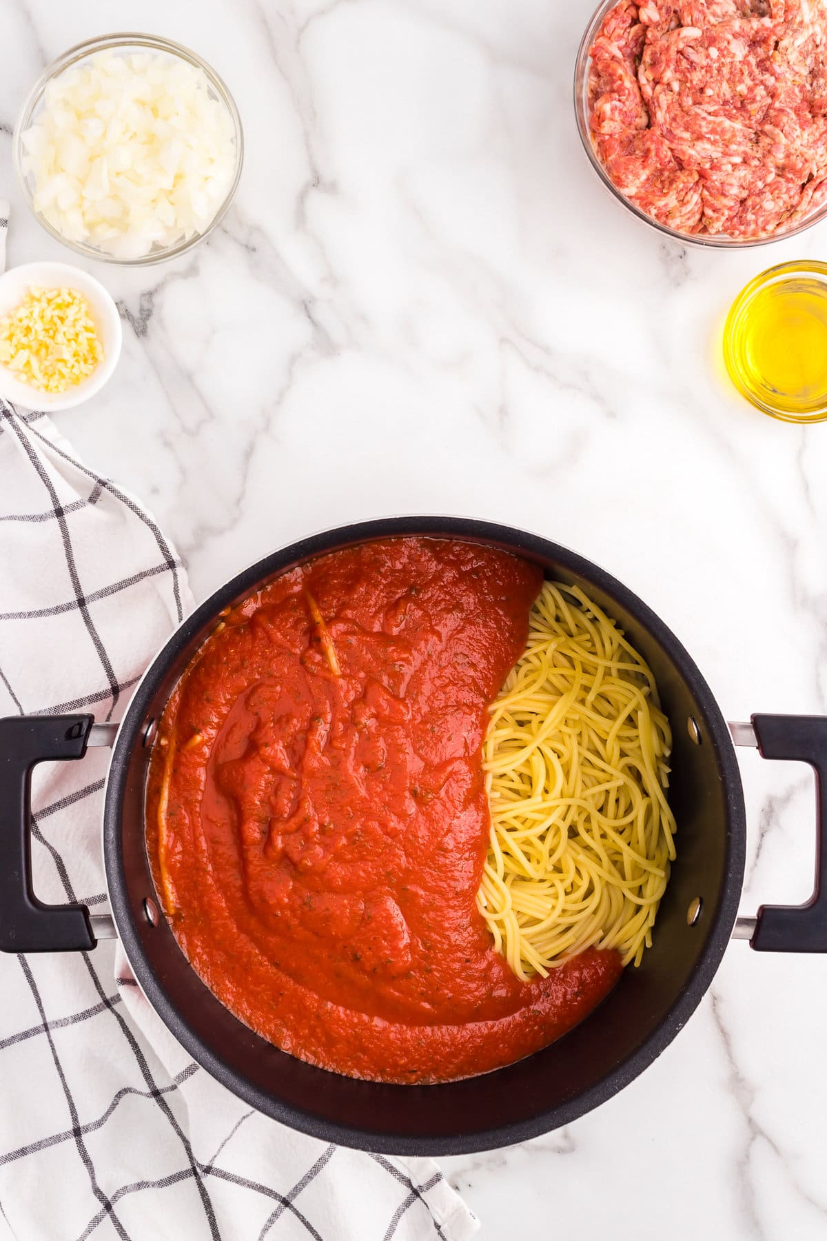 Combining cooked spaghetti noodles and spaghetti sauce in large stovetop pot for Million Dollar Spaghetti recipe