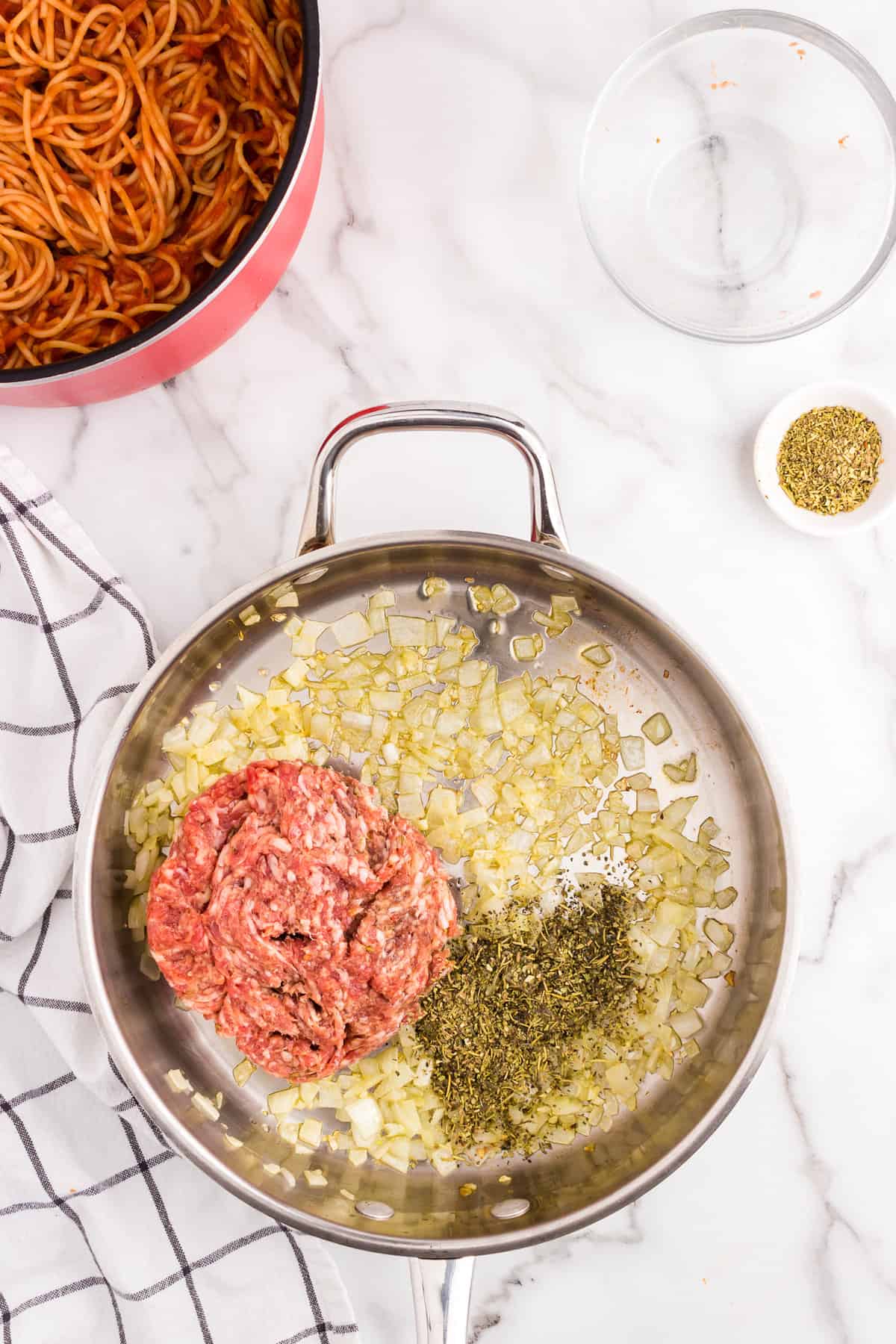 Cooking Italian sausage with onion and seasoning in stovetop skillet for Million Dollar Spaghetti recipe