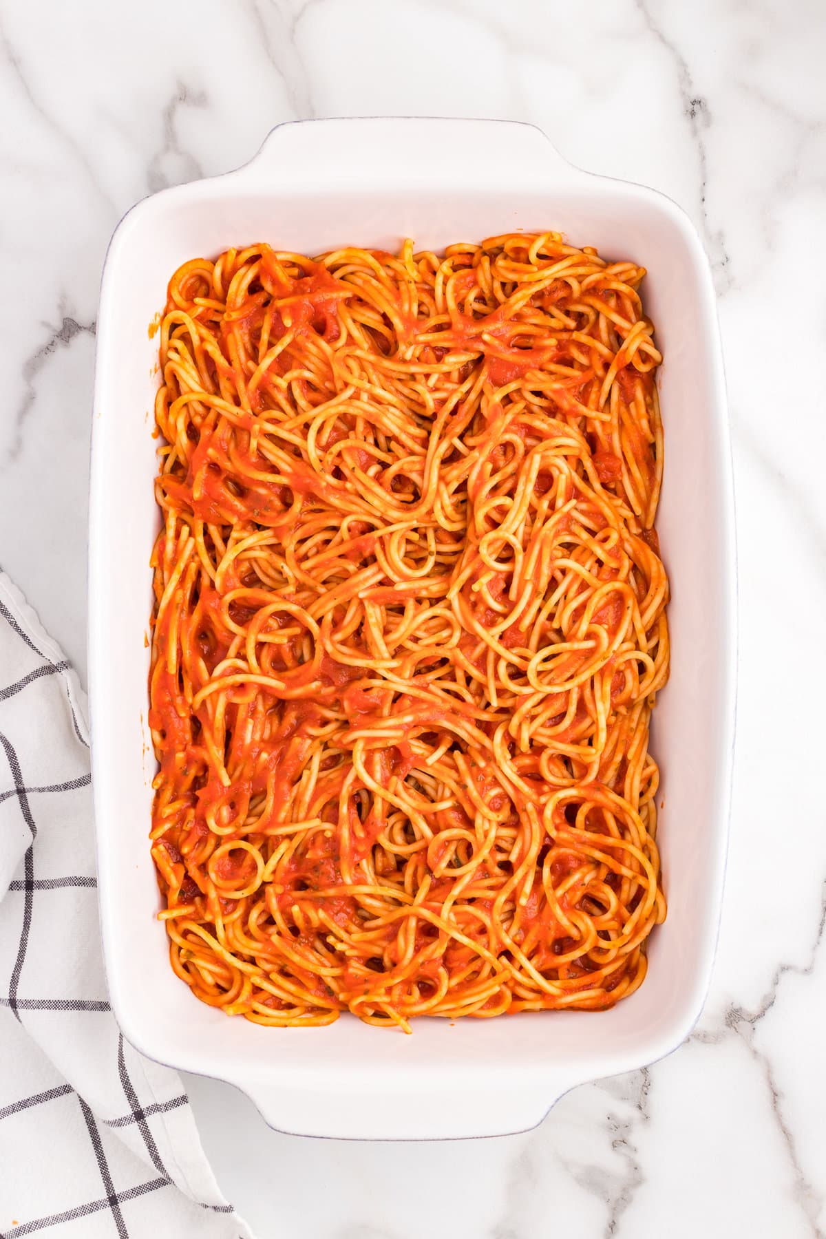 Spreading spaghetti noodles and sauce in 9x13 baking dish in Million Dollar Spaghetti