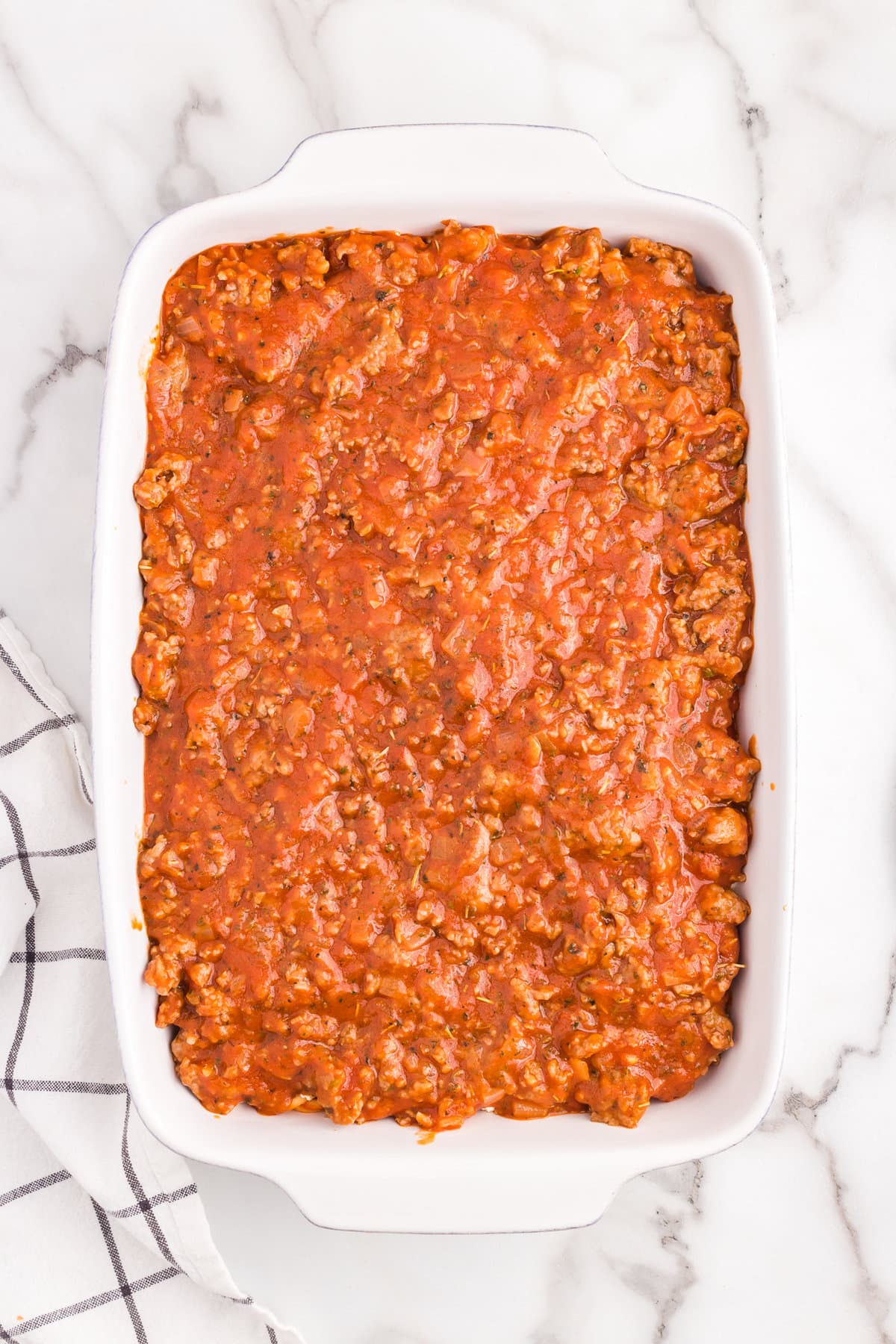 Topping cheese layer with Italian sausage and sauce layer for Million Dollar Spaghetti Casserole recipe
