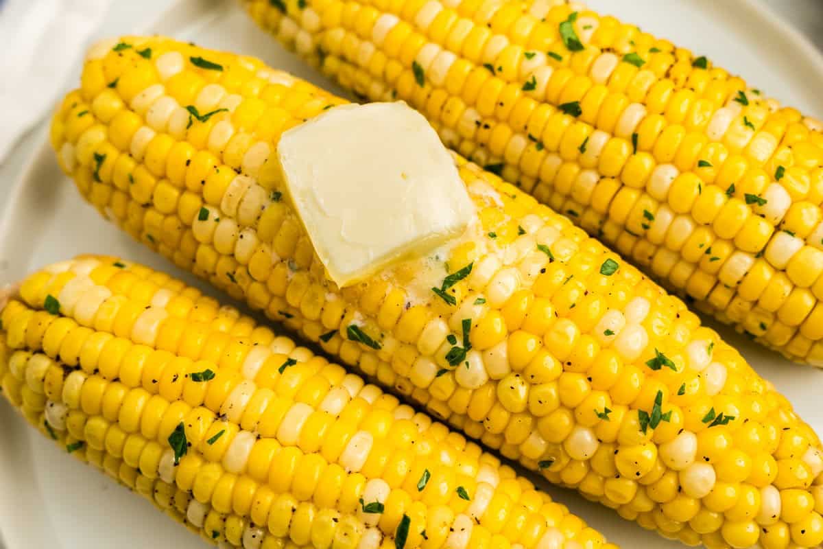 Crock Pot Corn on the Cob arranged on plate with a pad of butter melting