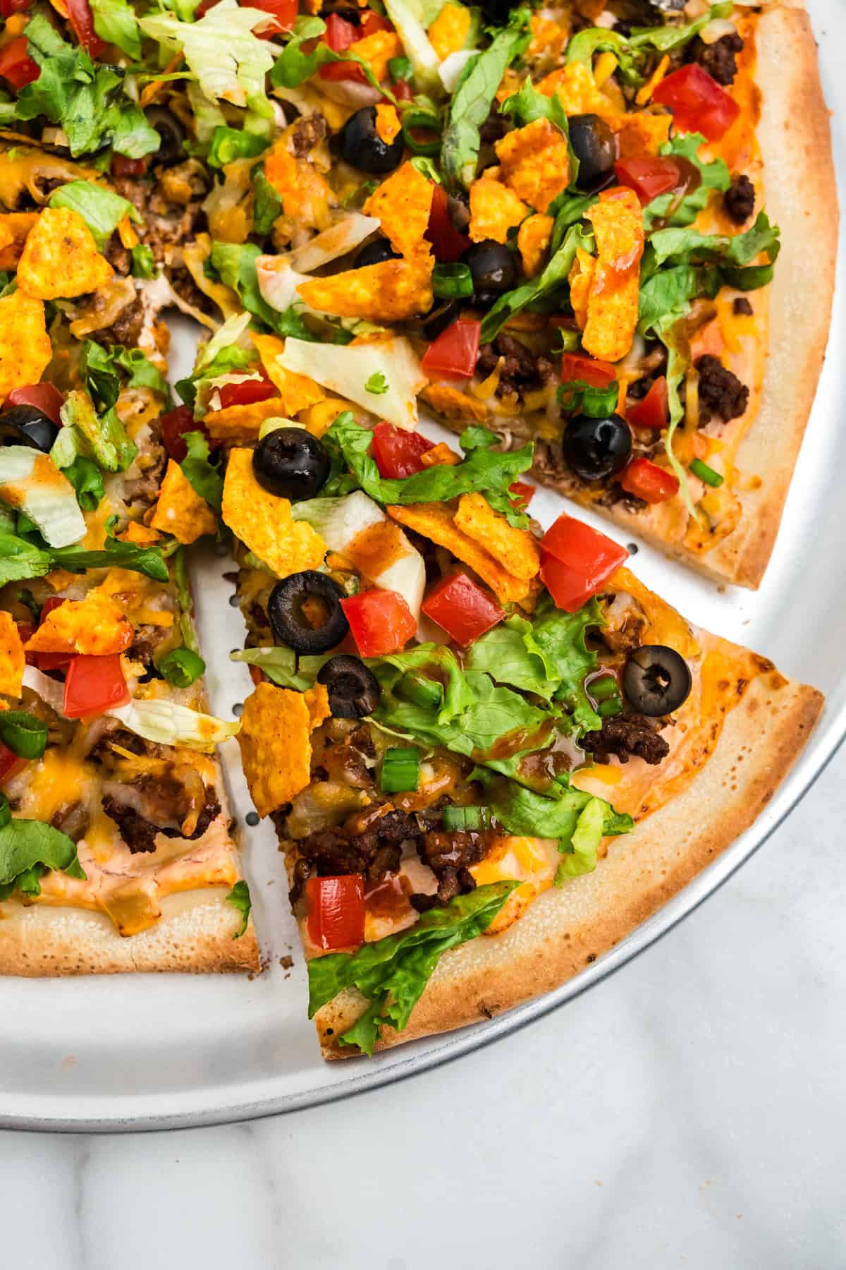 Taco Pizza on pizza pan with one slice cut