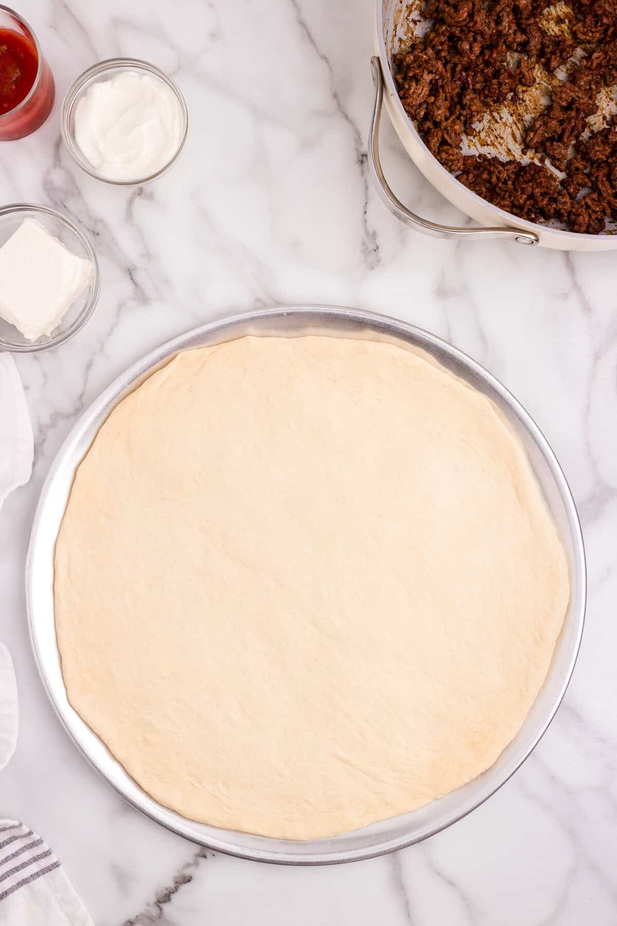 Pizza dough pressed on pizza tin for Taco Pizza