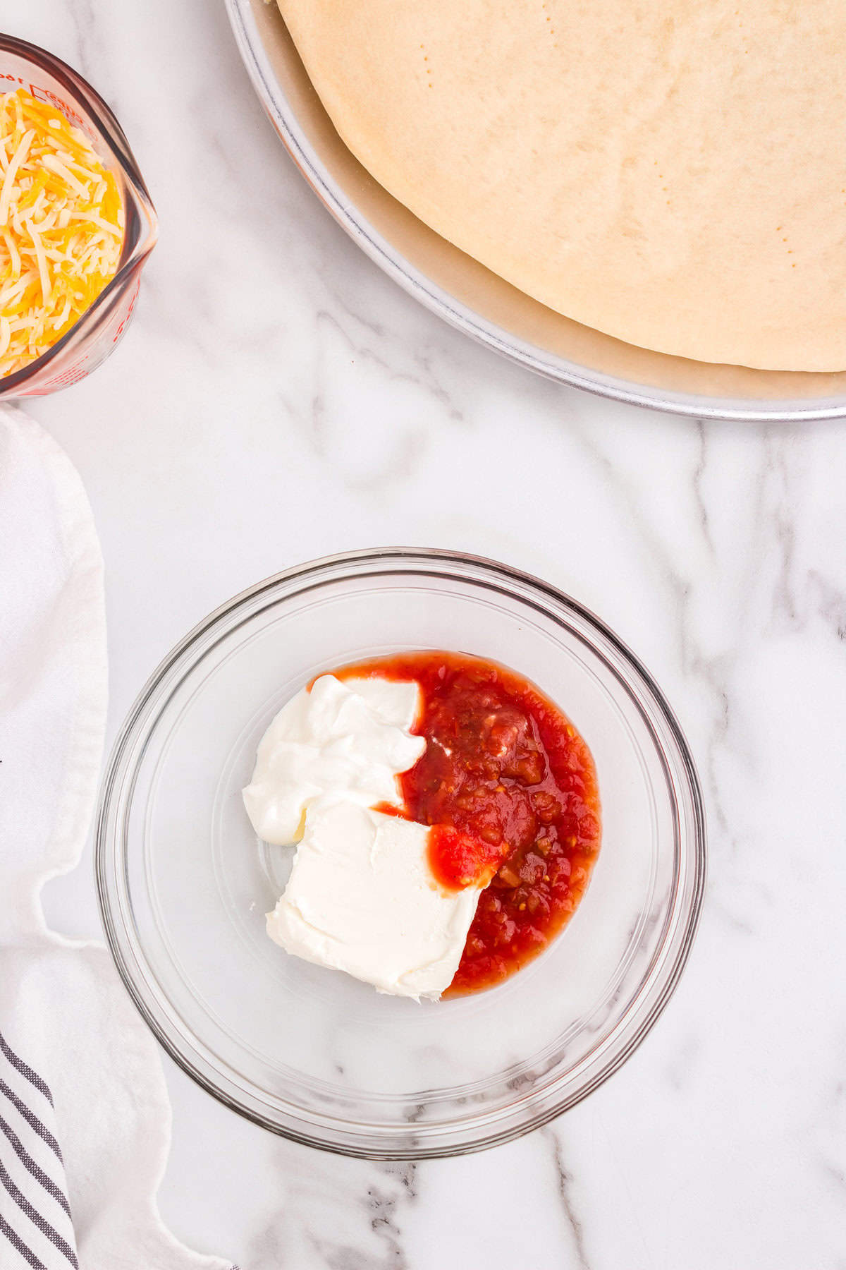Cream cheese and sour cream with salsa in small mixing bowl for Taco Pizza recipe