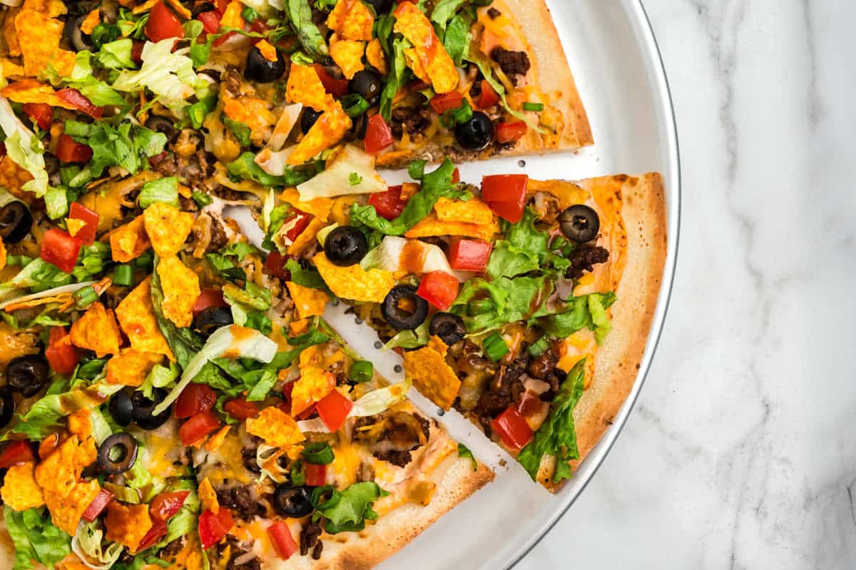 Taco Pizza on pizza pan with one slice cut